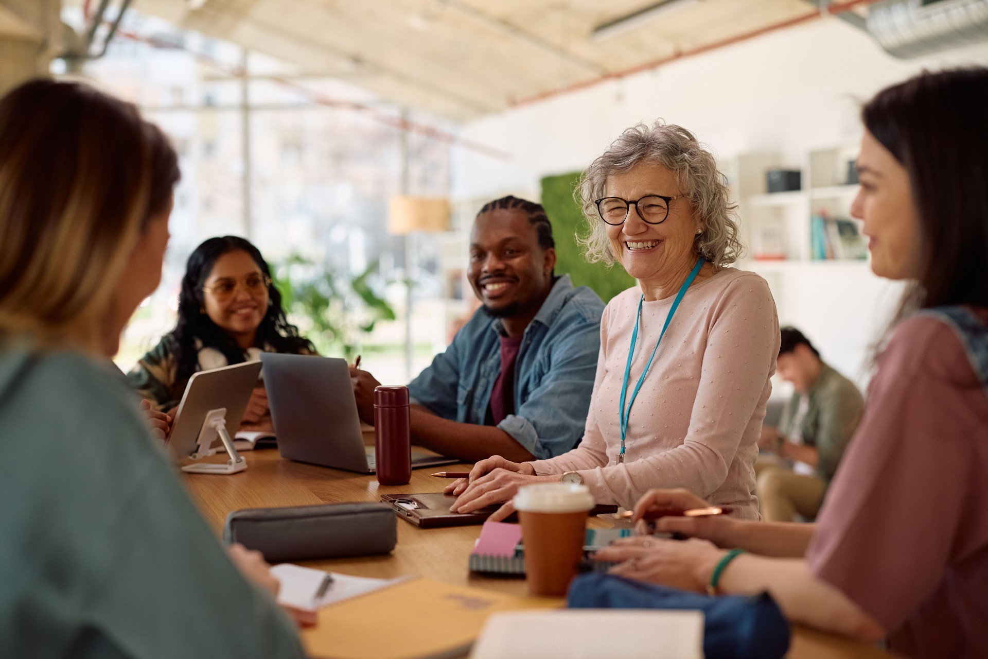 Happy university teacher communicating with her students in the classroom.